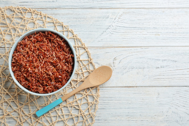 Photo of Delicious brown rice served on white wooden table, flat lay. Space for text