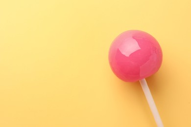 Photo of Tasty lollipop on yellow background, top view. Space for text