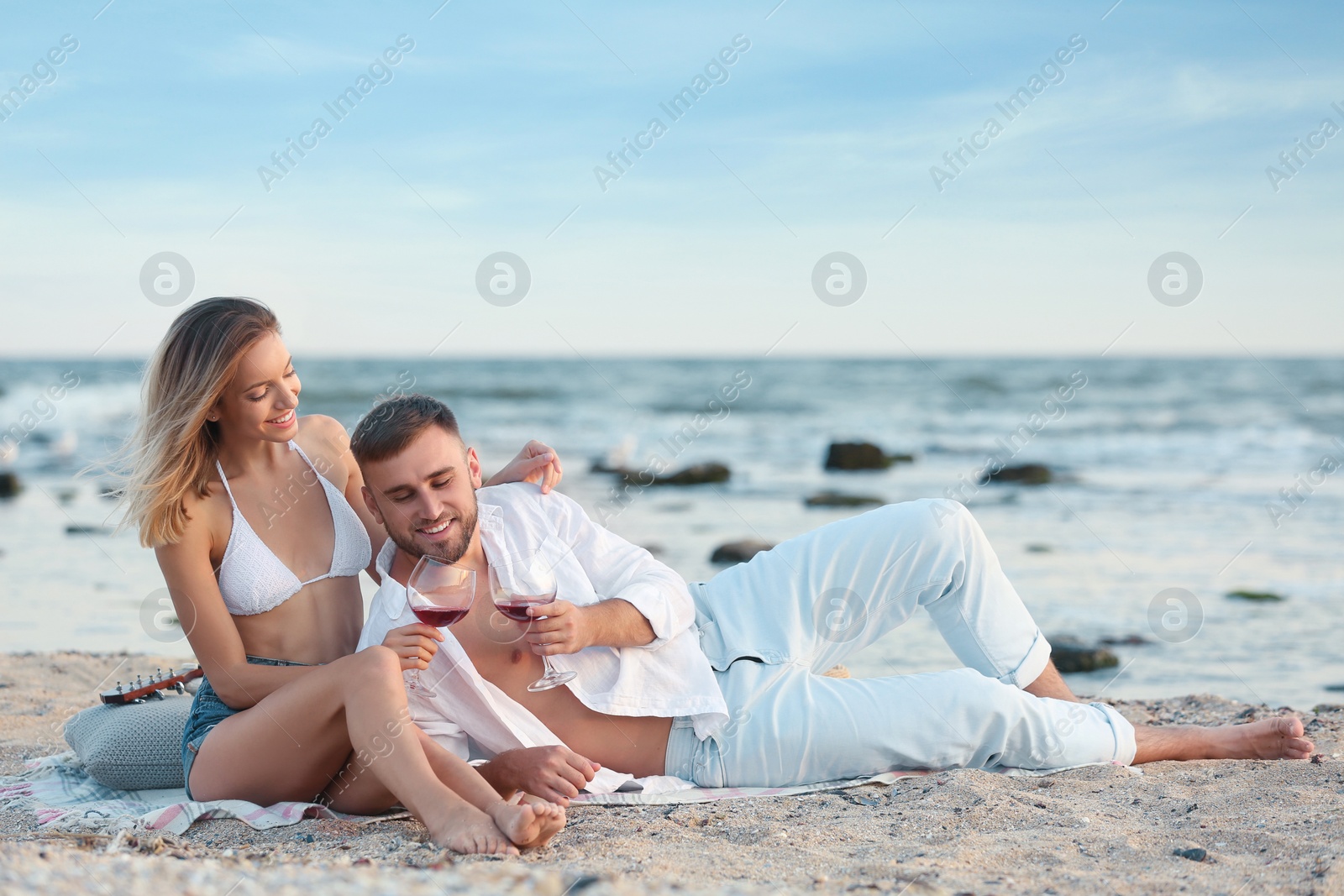 Photo of Young couple with glasses of wine on beach