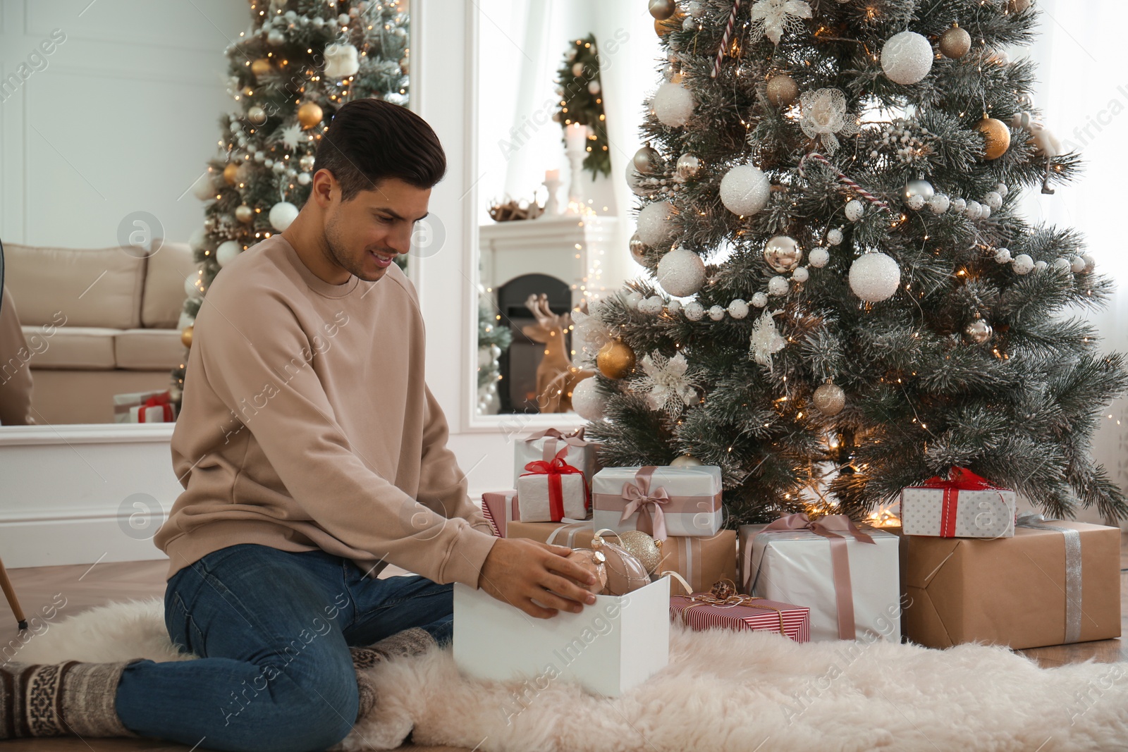 Photo of Man decorating Christmas tree in beautiful room interior