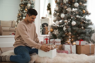 Photo of Man decorating Christmas tree in beautiful room interior