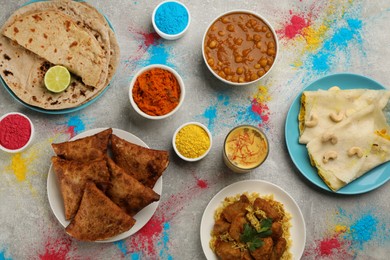 Traditional Indian food and color powders on grey table, flat lay. Holi festival celebration