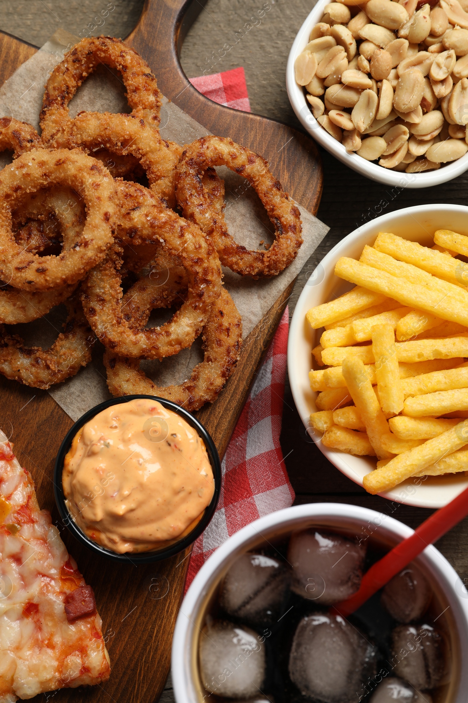 Photo of French fries, onion rings and other fast food on wooden table, flat lay