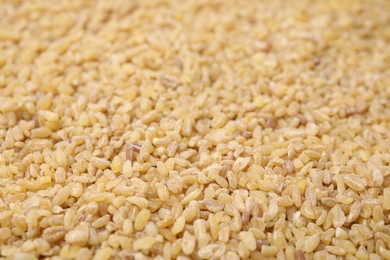 Photo of Uncooked organic bulgur as background, closeup view