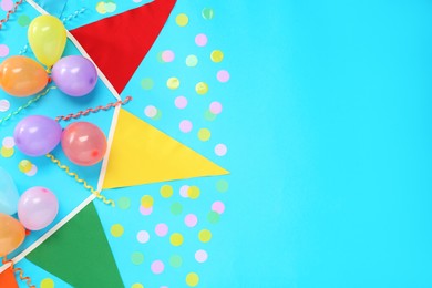 Photo of Bunting with colorful triangular flags, balloons, streamers and confetti on light blue background, flat lay. Space for text