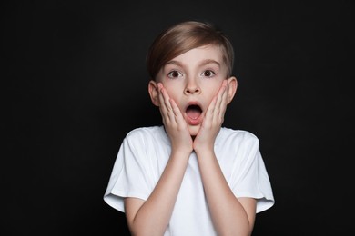 Photo of Little boy feeling fear on black background