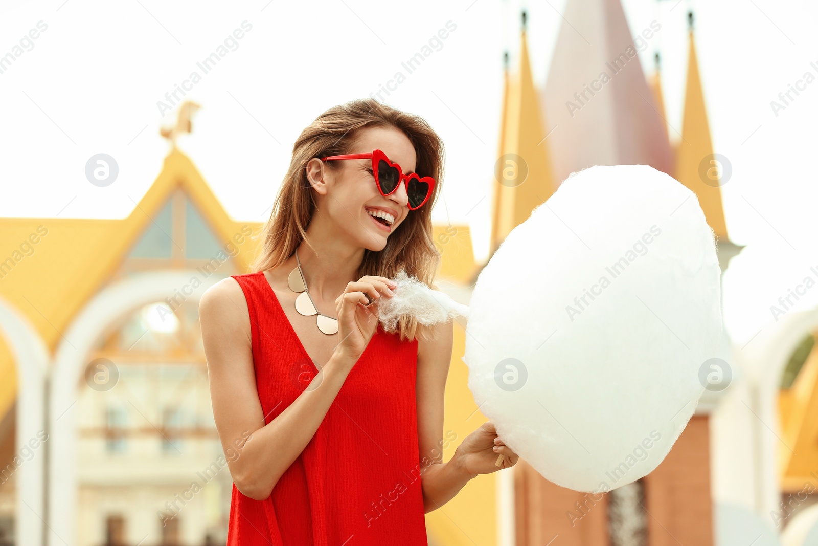 Photo of Happy young woman with cotton candy in amusement park