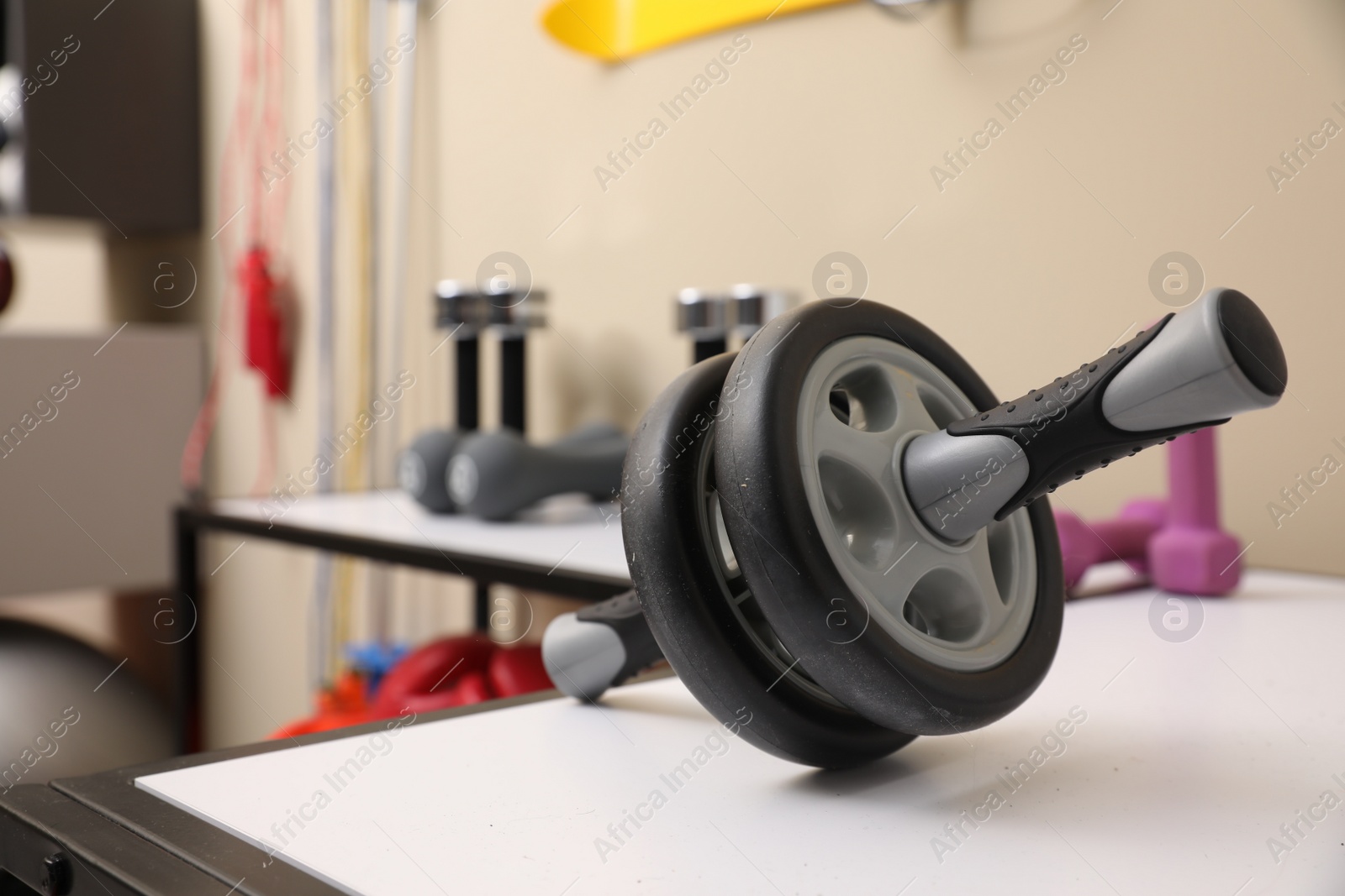 Photo of Abdominal wheel on white table in room with other sports equipment