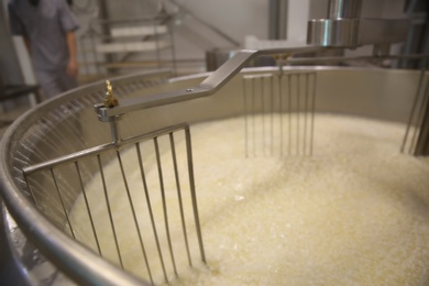 Photo of Adding water to curd and whey in tank at cheese factory, closeup