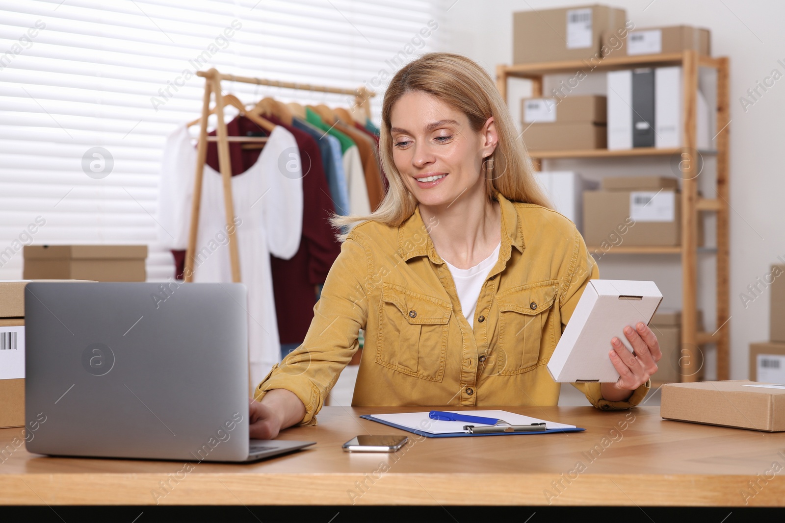 Photo of Seller with parcel and laptop working in office. Online store