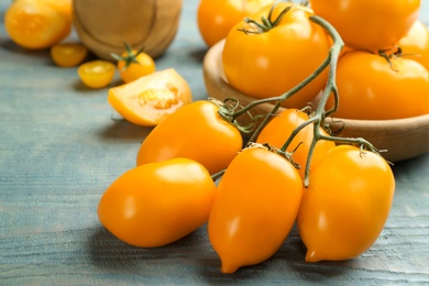 Photo of Ripe yellow tomatoes on light blue wooden table, closeup
