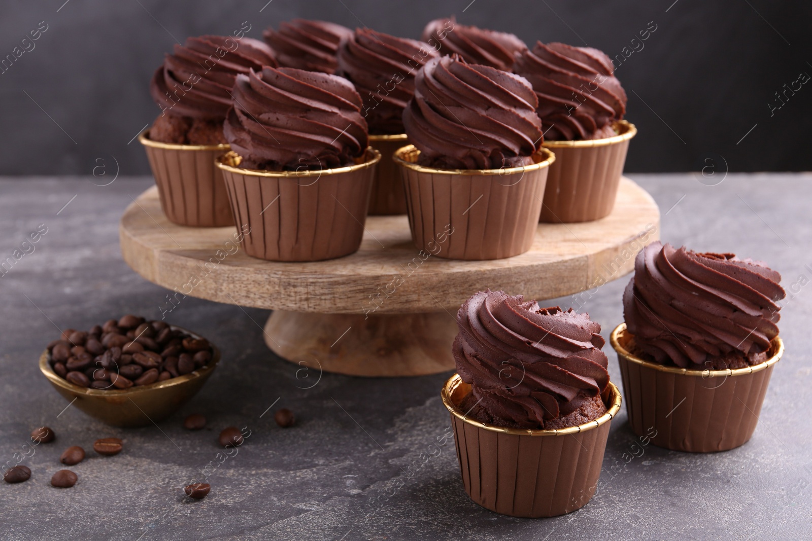 Photo of Delicious chocolate cupcakes and coffee beans on grey textured table
