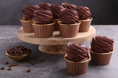 Delicious chocolate cupcakes and coffee beans on grey textured table