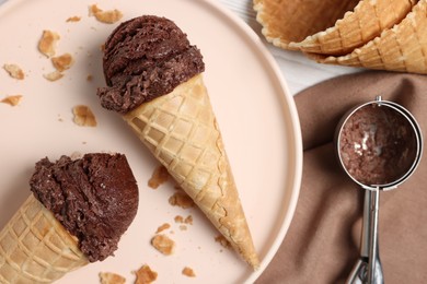 Chocolate ice cream scoops in wafer cones on table, flat lay
