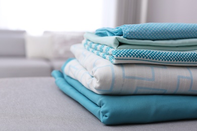 Photo of Stack of clean bed linens in room, closeup. Space for text