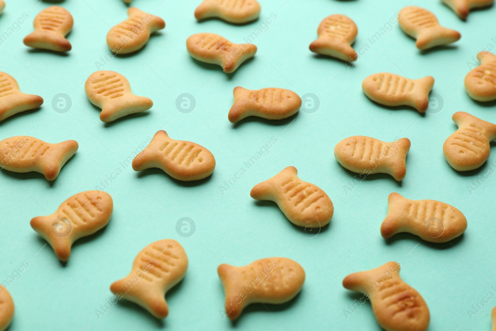 Photo of Delicious goldfish crackers on turquoise background, closeup