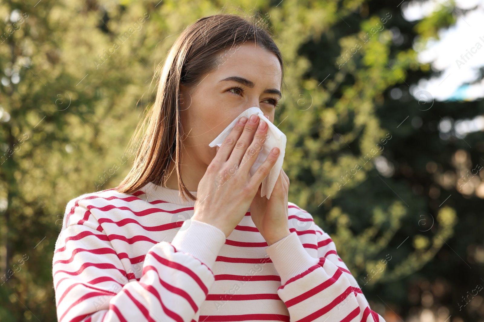 Photo of Woman with napkin suffering from seasonal allergy outdoors