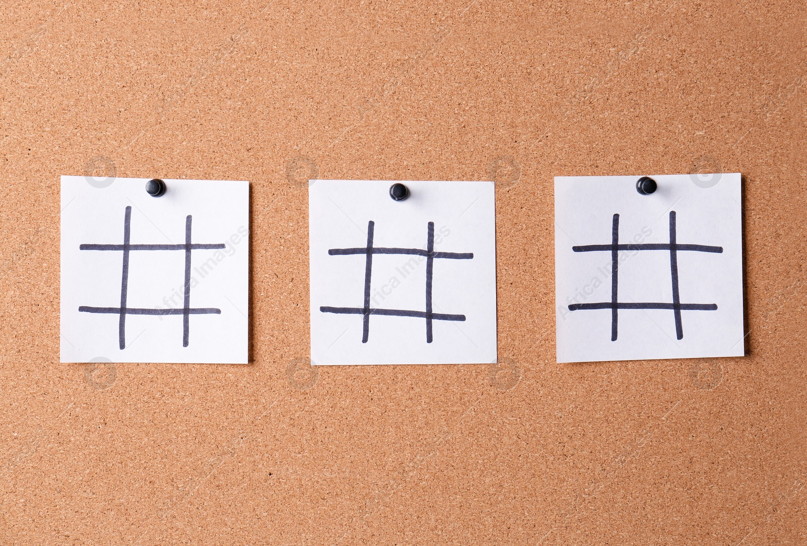 Photo of White note papers with hashtag symbols pinned on corkboard