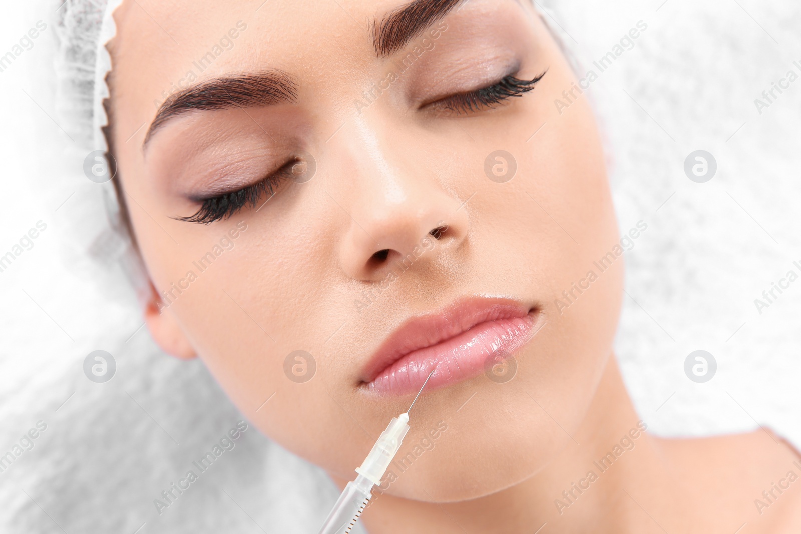 Photo of Young woman getting lip injection in beautician salon, closeup