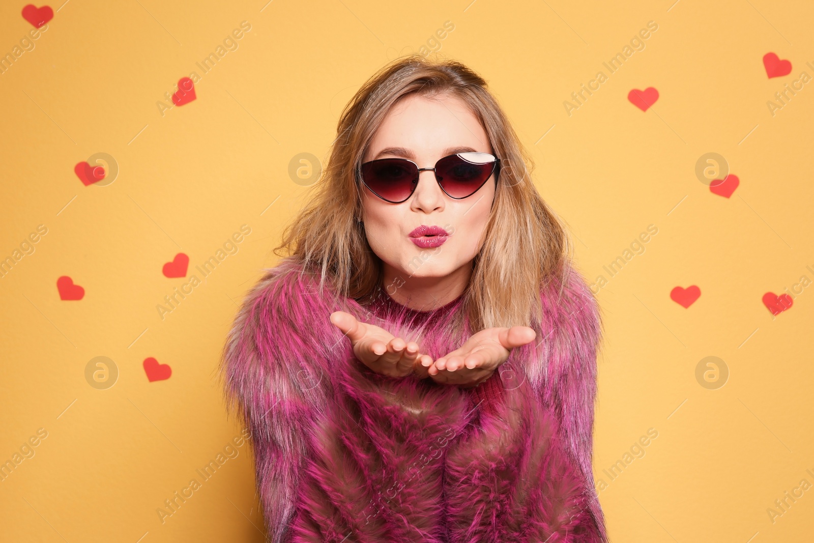 Photo of Beautiful young woman in fur coat with sunglasses posing on color background