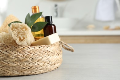 Photo of Natural loofah sponges in wicker basket on table indoors. Space for text