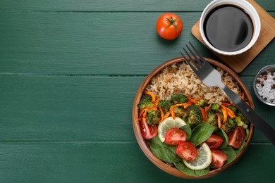 Photo of Tasty fried rice with vegetables served on green wooden table, flat lay. Space for text