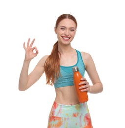 Young woman in sportswear with thermo bottle showing OK gesture on white background