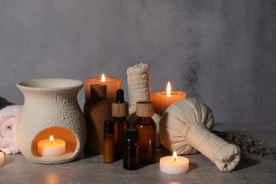 Photo of Aromatherapy. Scented candles and spa products on gray textured table