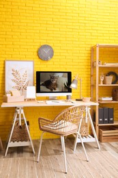 Photo of Stylish home office interior with comfortable workplace near yellow brick wall