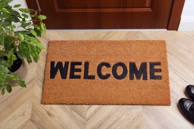 Photo of New clean brown mat with word Welcome near entrance door
