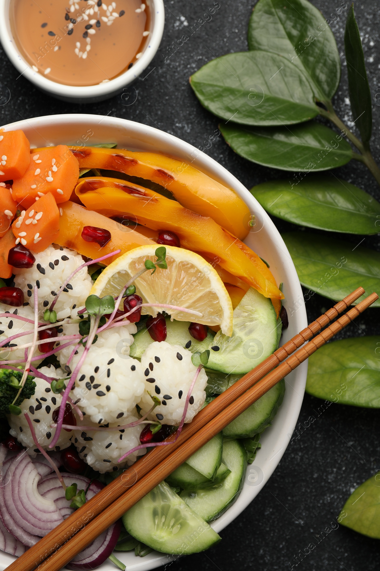 Photo of Bowl with many different vegetables and rice on grey textured table, flat lay. Vegan diet