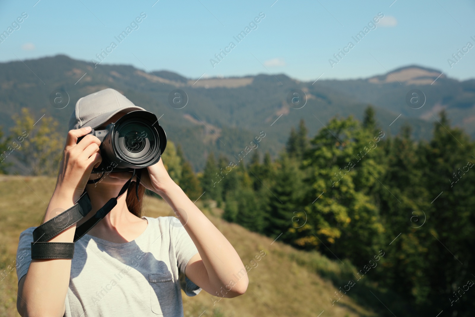 Photo of Professional photographer taking picture with modern camera in mountains. Space for text