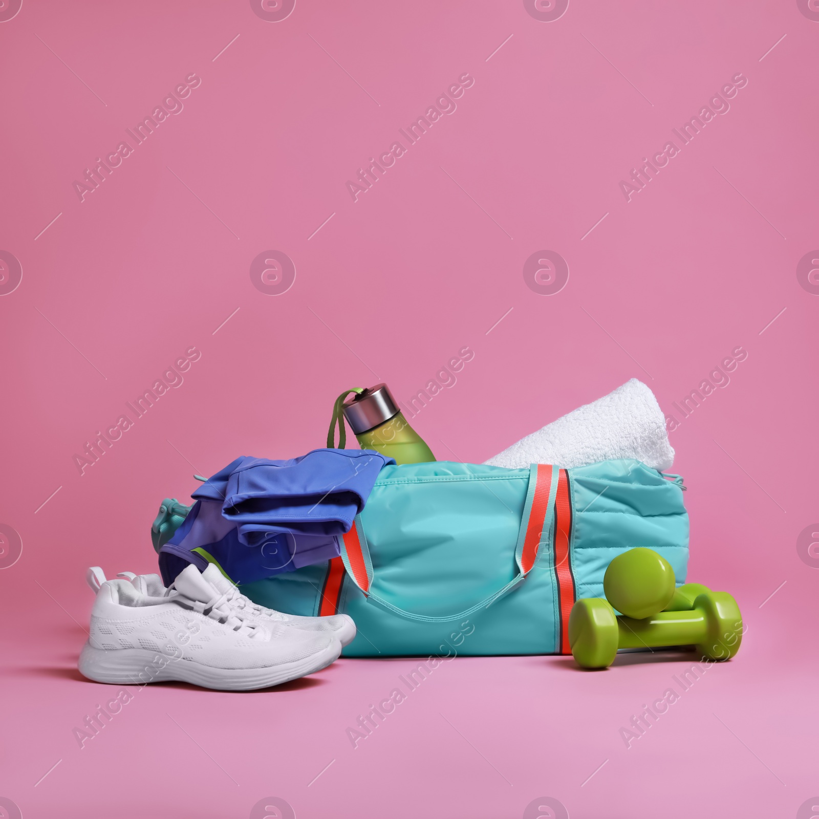 Photo of Blue gym bag and sports accessories on pink background