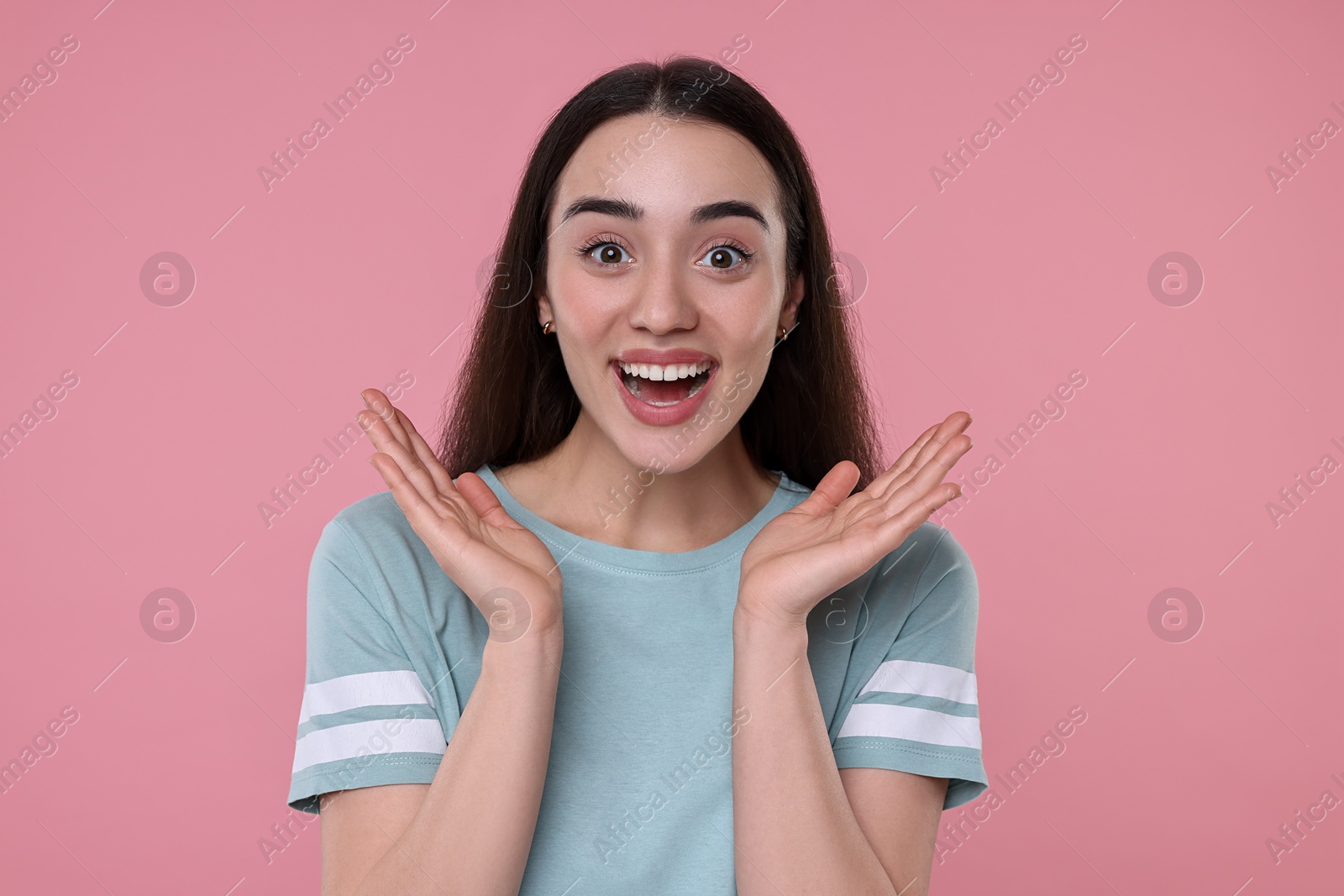 Photo of Portrait of happy surprised woman on pink background