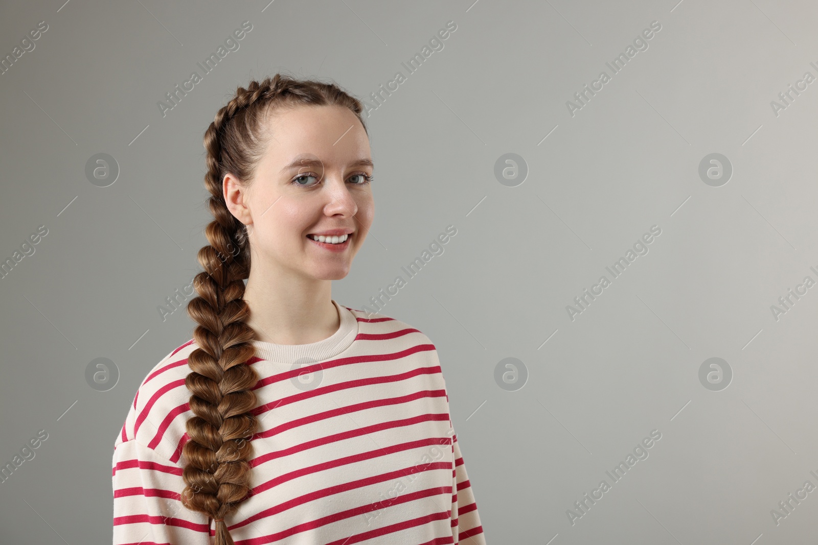 Photo of Woman with braided hair on grey background, space for text