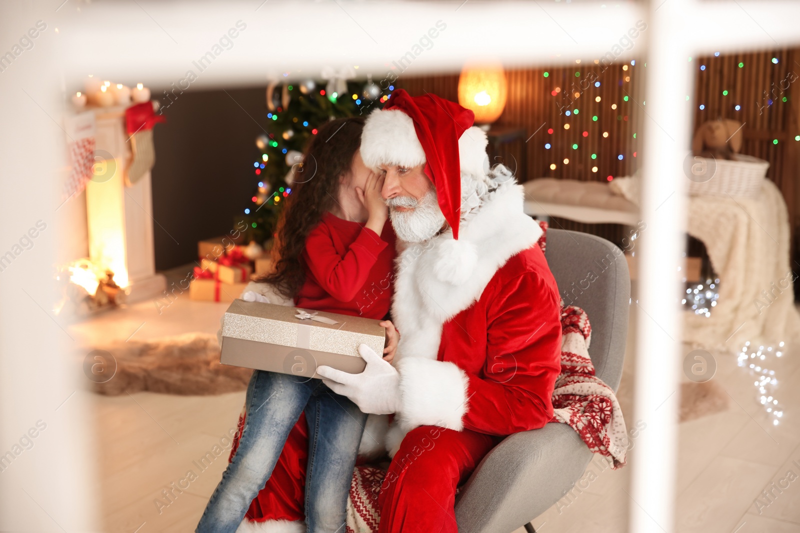 Photo of Little child with Santa Claus and Christmas gift at home, view through window