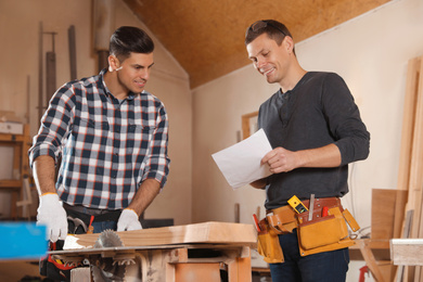 Photo of Professional carpenters working with draft in workshop