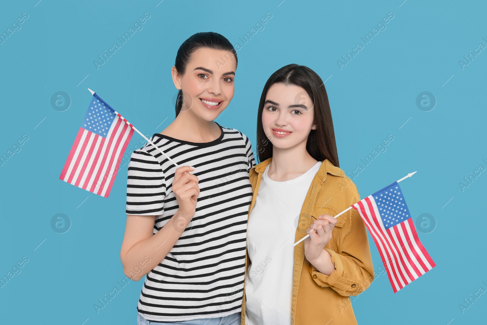 Photo of 4th of July - Independence Day of USA. Happy woman and her daughter with American flags on light blue background