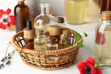 Photo of Aromatherapy. Different essential oils and flowers on white wooden table