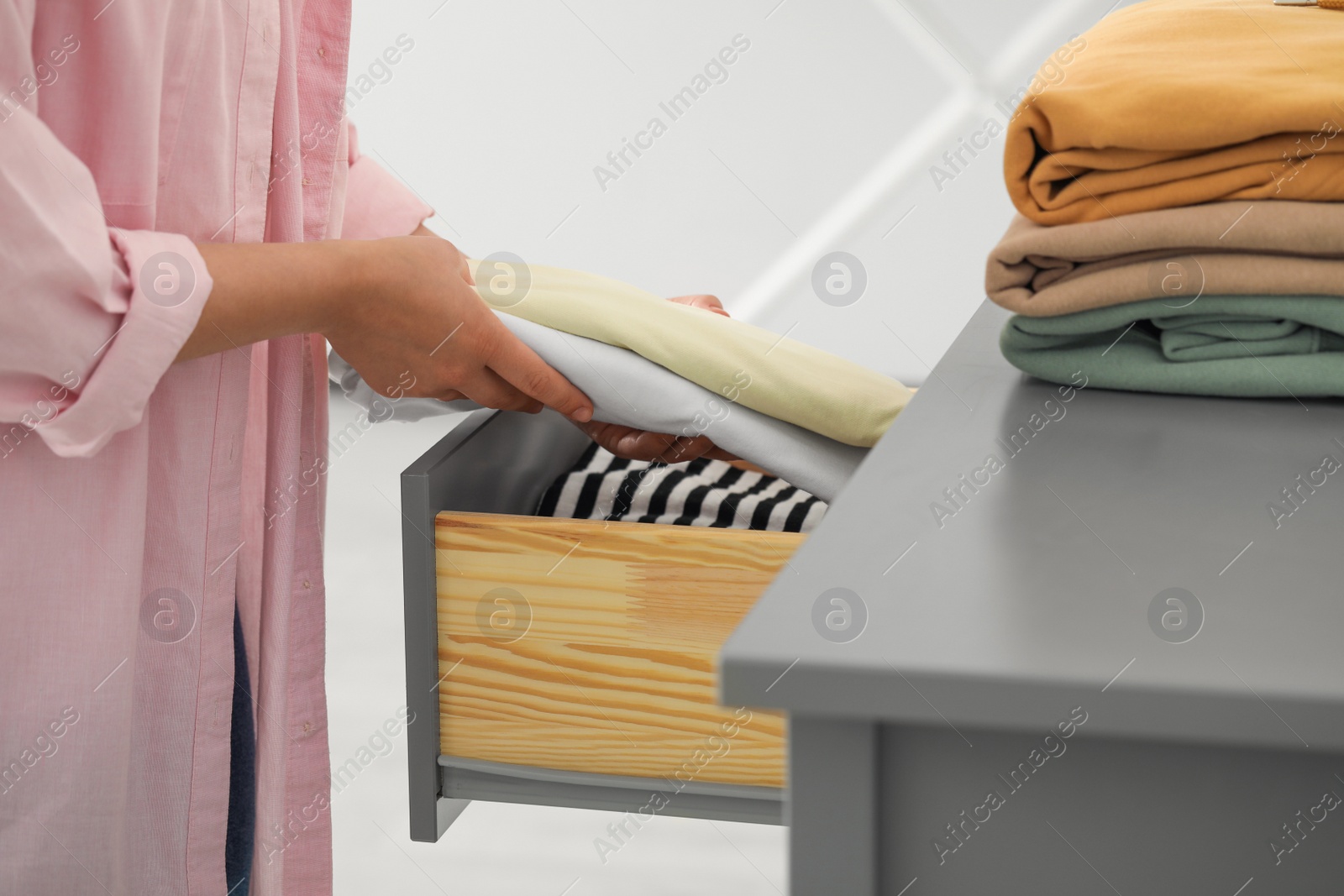 Photo of Woman putting clean clothes into drawer at home, closeup