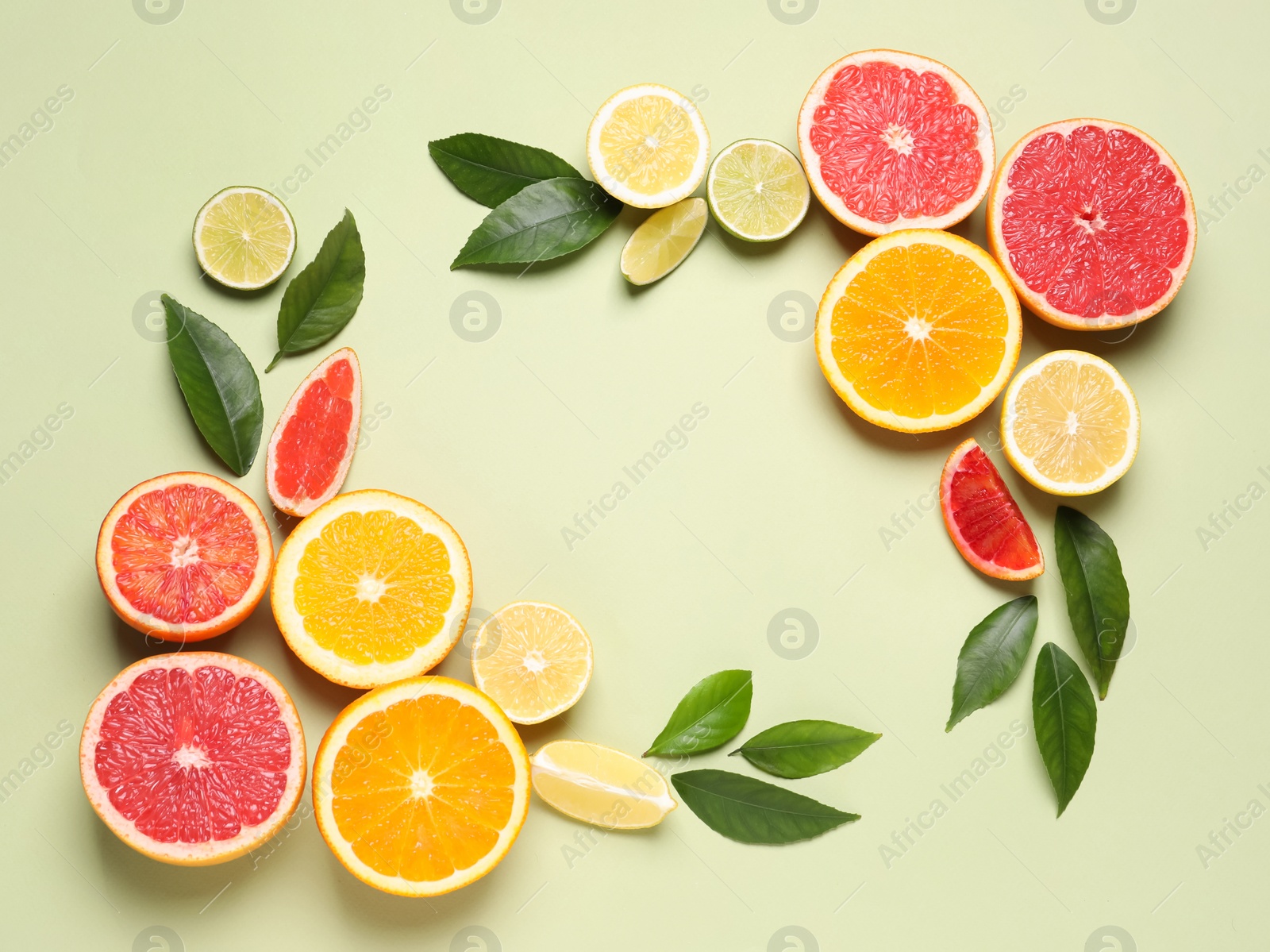 Photo of Frame of fresh juicy citrus fruits with green leaves on light background, flat lay. Space for text