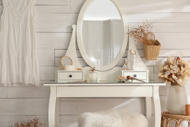 Wooden dressing table with decorative elements and makeup products in room