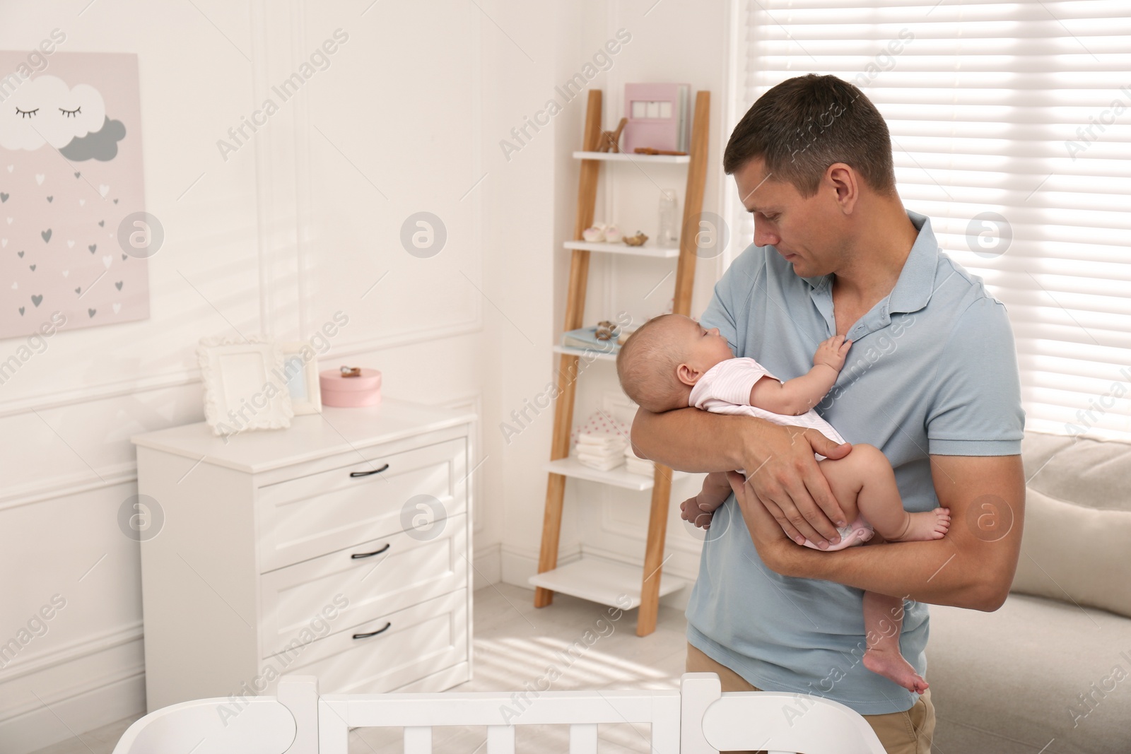 Photo of Happy father with his cute sleeping baby near crib at home