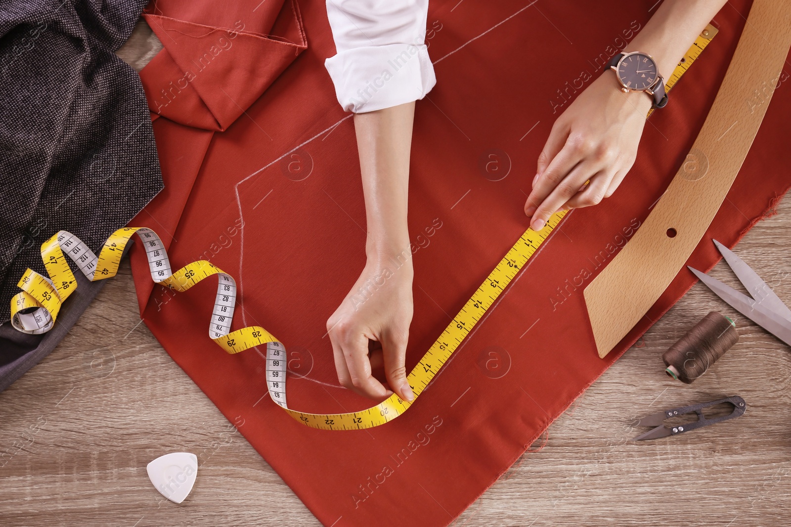 Photo of Tailor working with cloth at table in atelier, top view