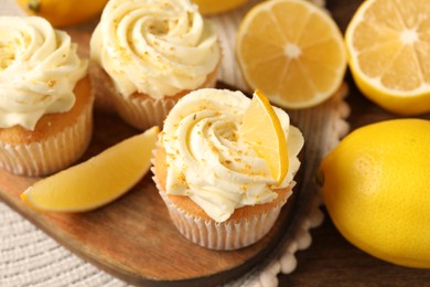 Tasty cupcakes with cream, zest and lemons on wooden table, closeup