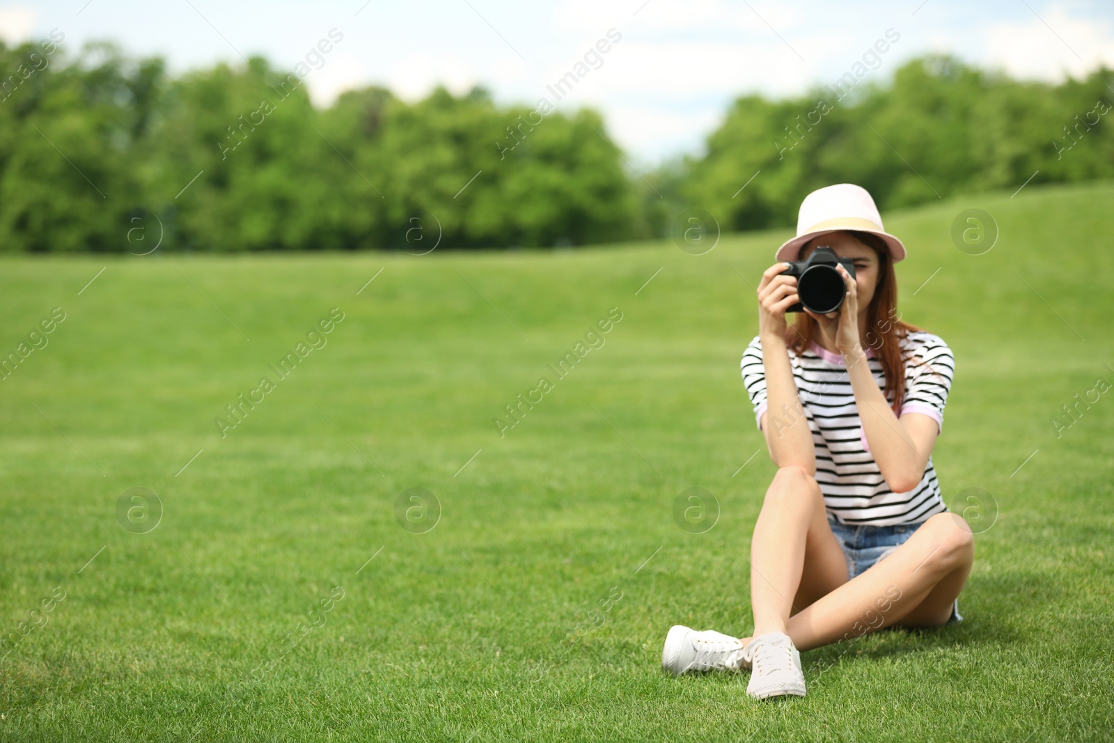 Photo of Photographer taking photo with professional camera in park. Space for text