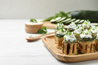 Photo of Tasty stuffed zucchini rolls on white wooden table. Space for text