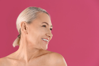 Photo of Portrait of beautiful mature woman on pink background. Space for text