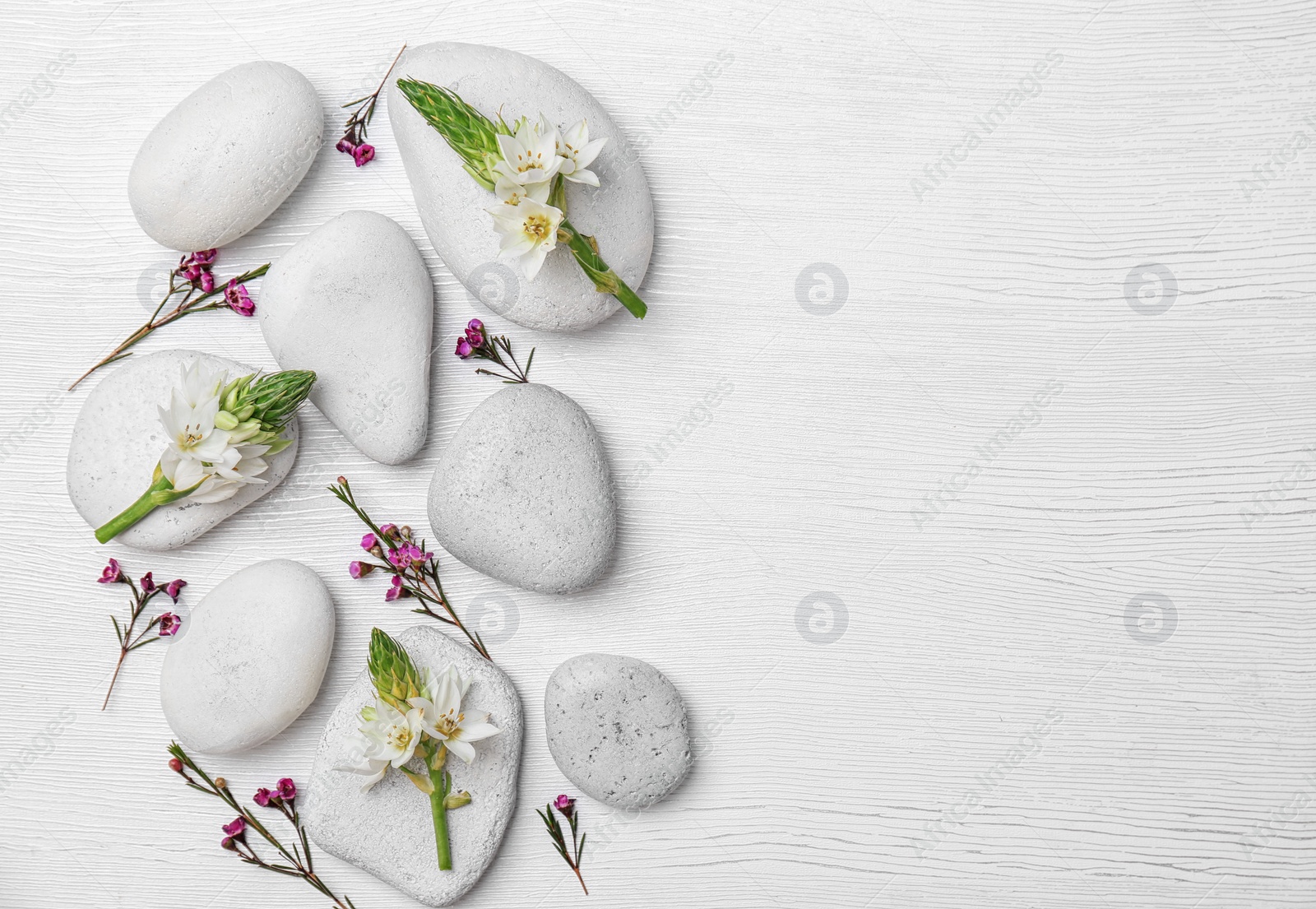 Photo of Spa stones and beautiful flowers on wooden background