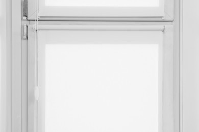 Photo of Window with closed white roller blinds indoors